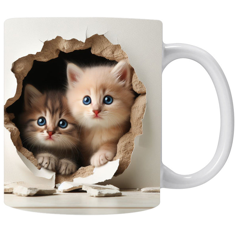White mug with two kittens peering through a cardboard hole design on a white background
