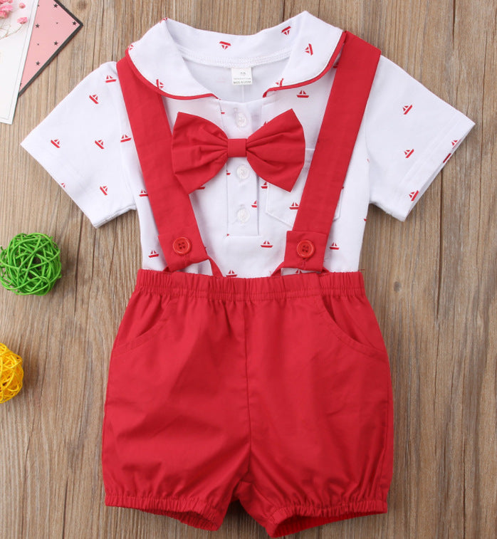 Children's outfit with white shirt, red bow tie, and red shorts on a wooden surface.