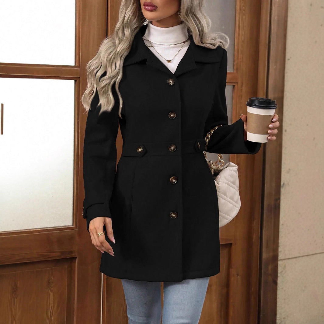 Woman in a black coat holding a coffee cup, standing in front of a wooden door.