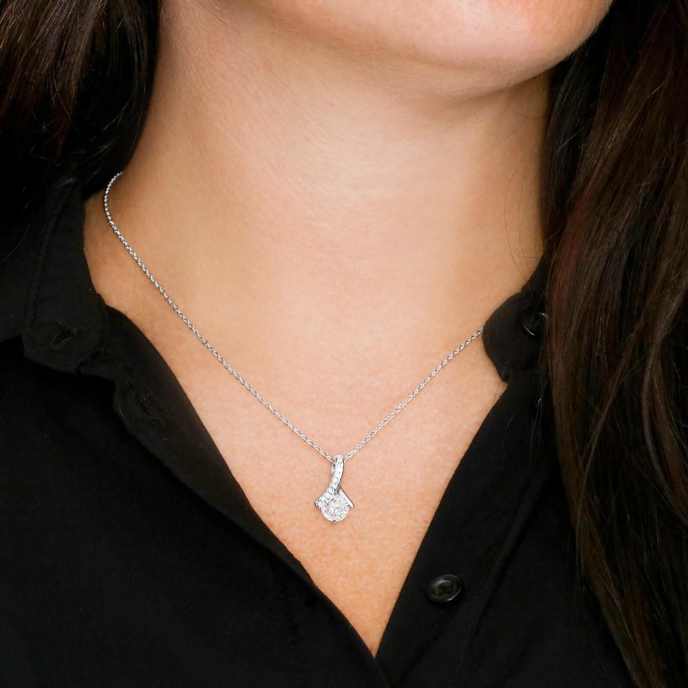 Silver necklace with a pendant worn by a person against a black shirt background