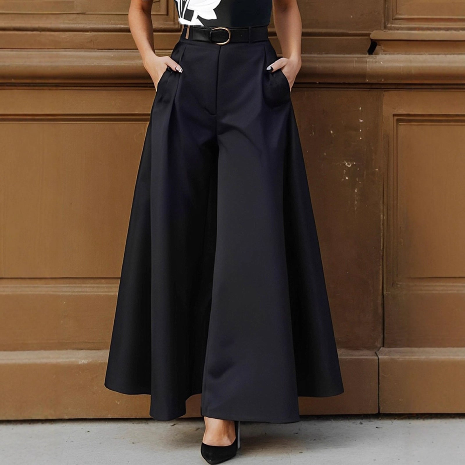 Person wearing black wide-leg pants against a brown paneled wall.