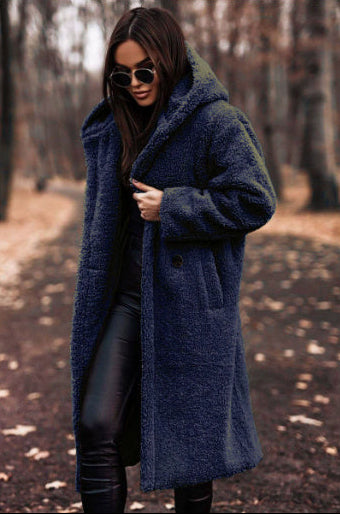 Woman wearing a blue coat in a forest setting