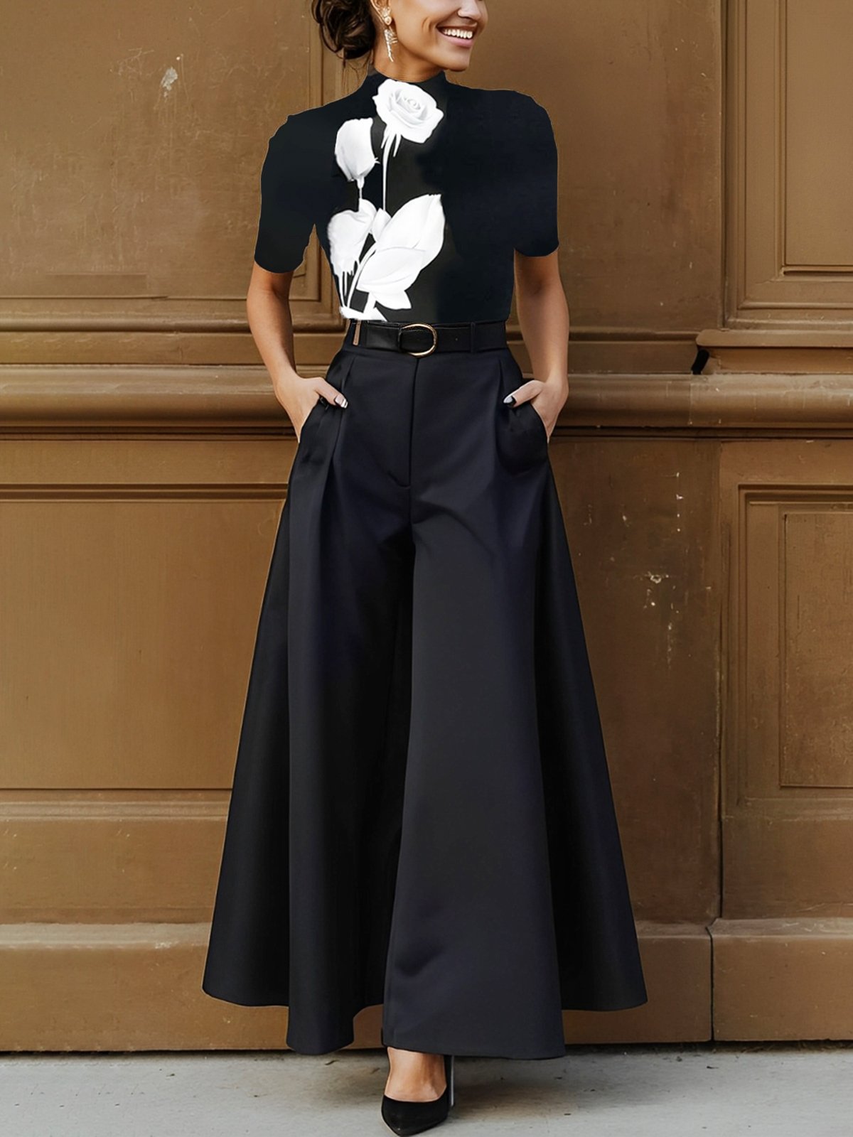 Woman wearing a black outfit with white floral details against a brown wall.
