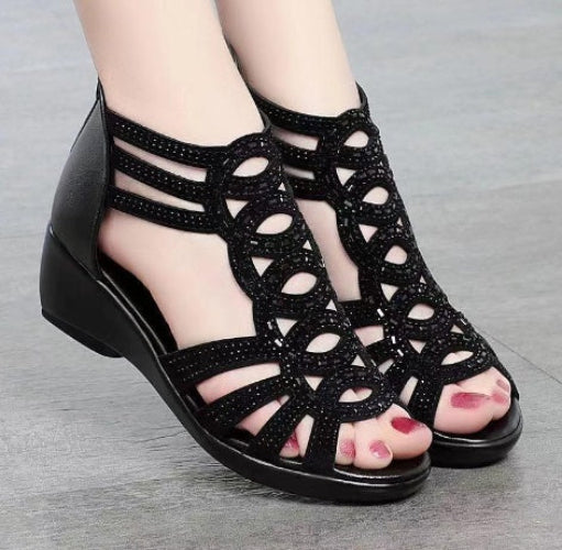 Black open-toe sandals with glittery detailing on a gray background