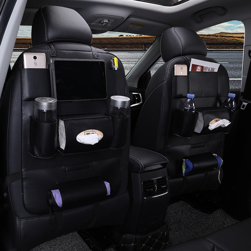 Car interior with black seat back organizers and various items on the seats.