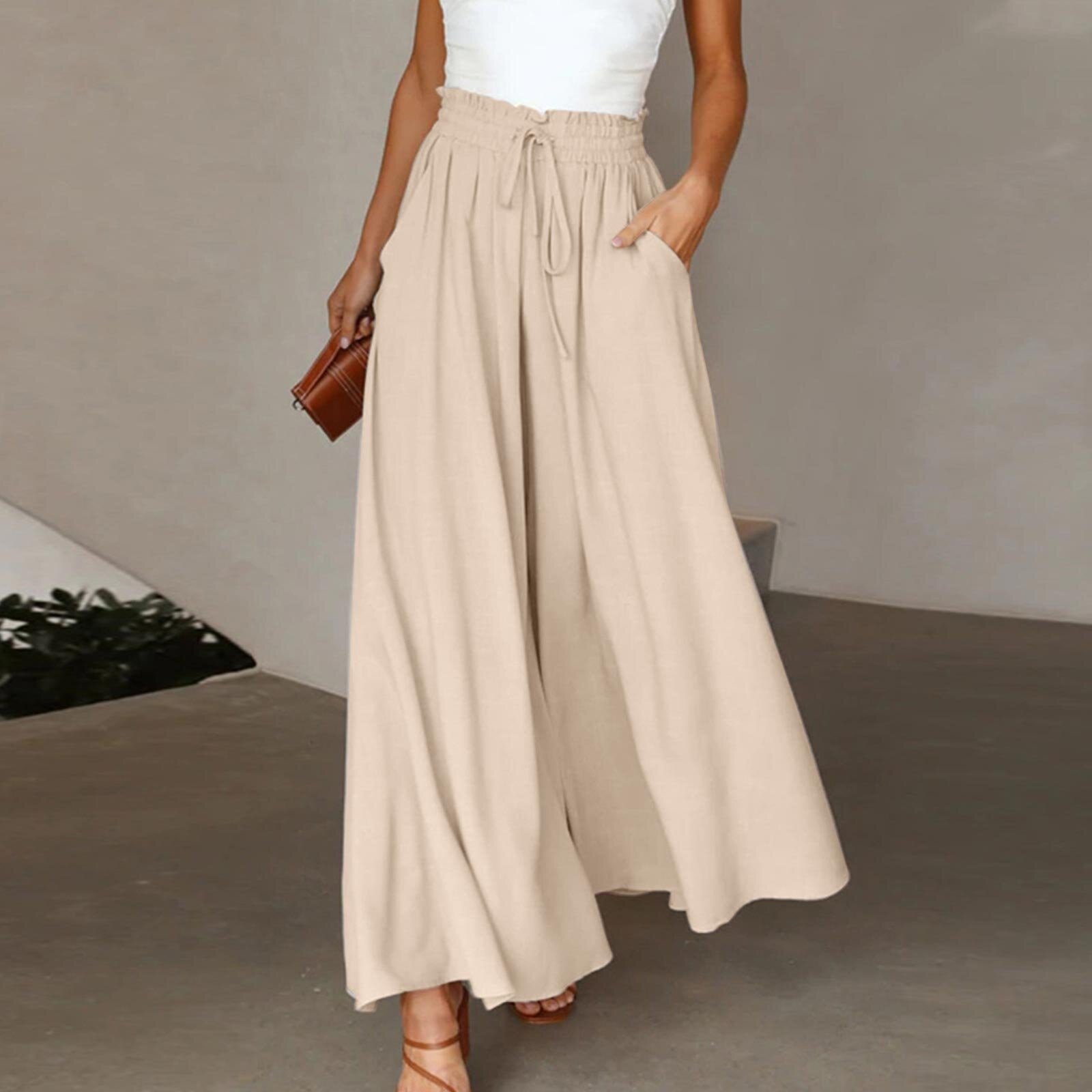 Person wearing a beige wide-leg pants and white top in an indoor setting.