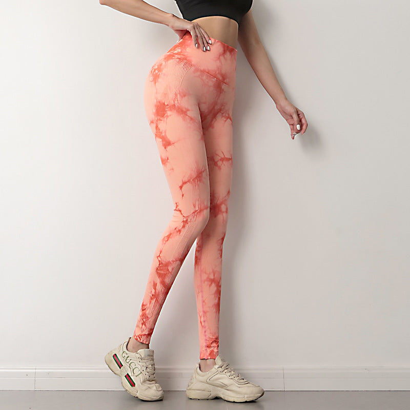 Person wearing pink tie-dye leggings and white sneakers against a plain background