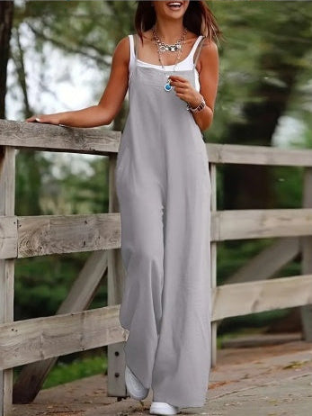 Woman in a long gray dress standing on a wooden bridge with a blurred natural background