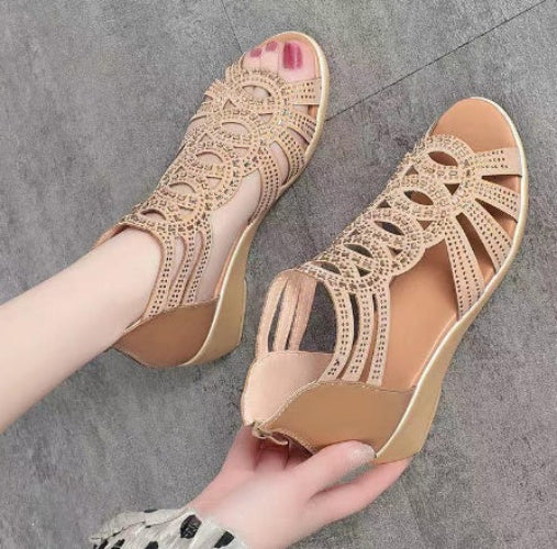 Beige open-toe sandals with detailed lace-up design on a gray floor.