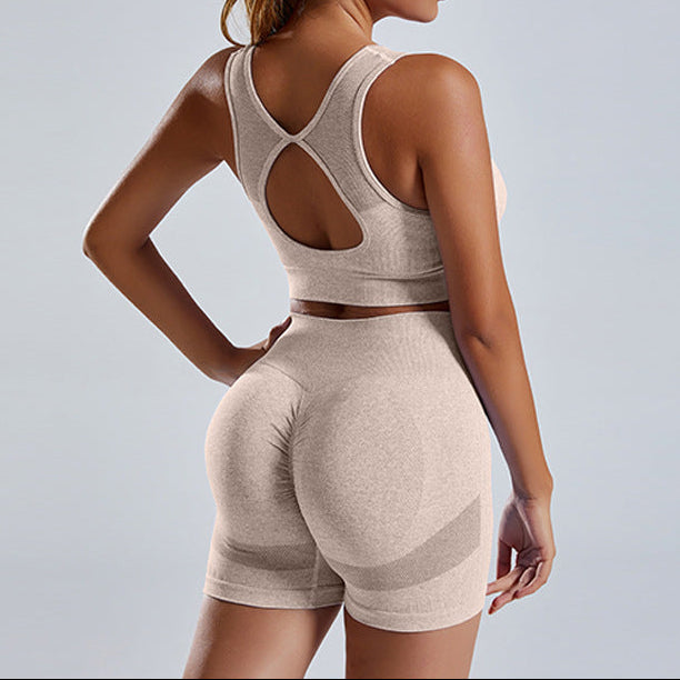 Woman wearing a beige sports bra and shorts set on a light gray background