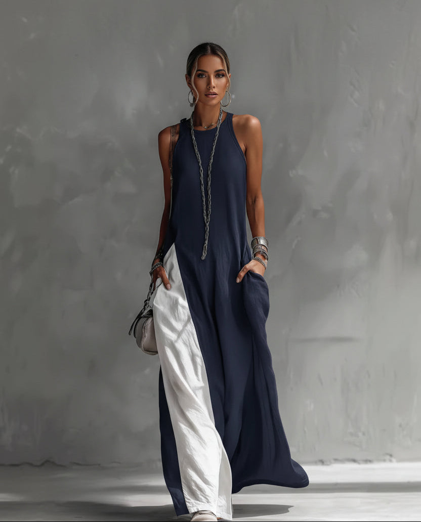 Person wearing a long navy dress with white pants against a gray background