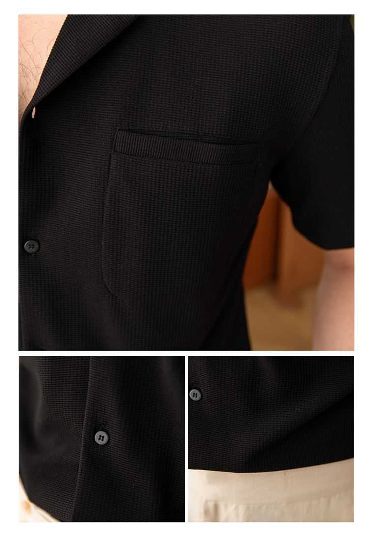 Close-up of a black textured shirt with buttons and a pocket, worn by a person.