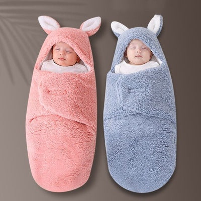 Two baby swaddles, one pink and one blue, with bunny ears on a gray background.