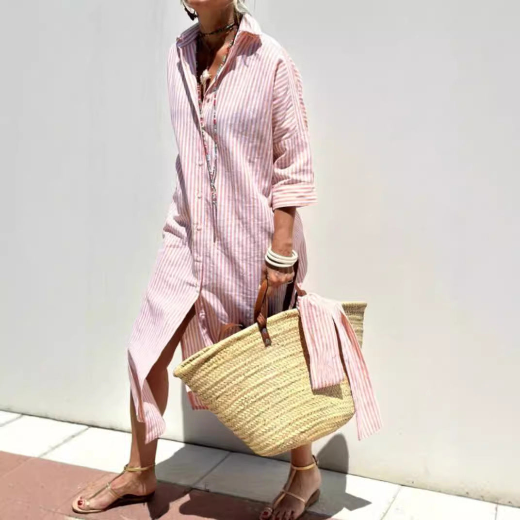 Person wearing a pink striped dress holding a straw bag against a white background