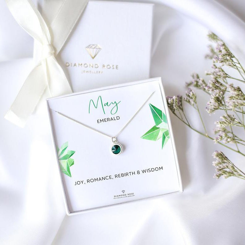Diamond Rose jewelry box with a necklace featuring an emerald stone on a white background.