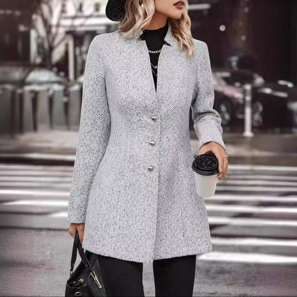 Woman in a gray coat holding a coffee cup on a city street