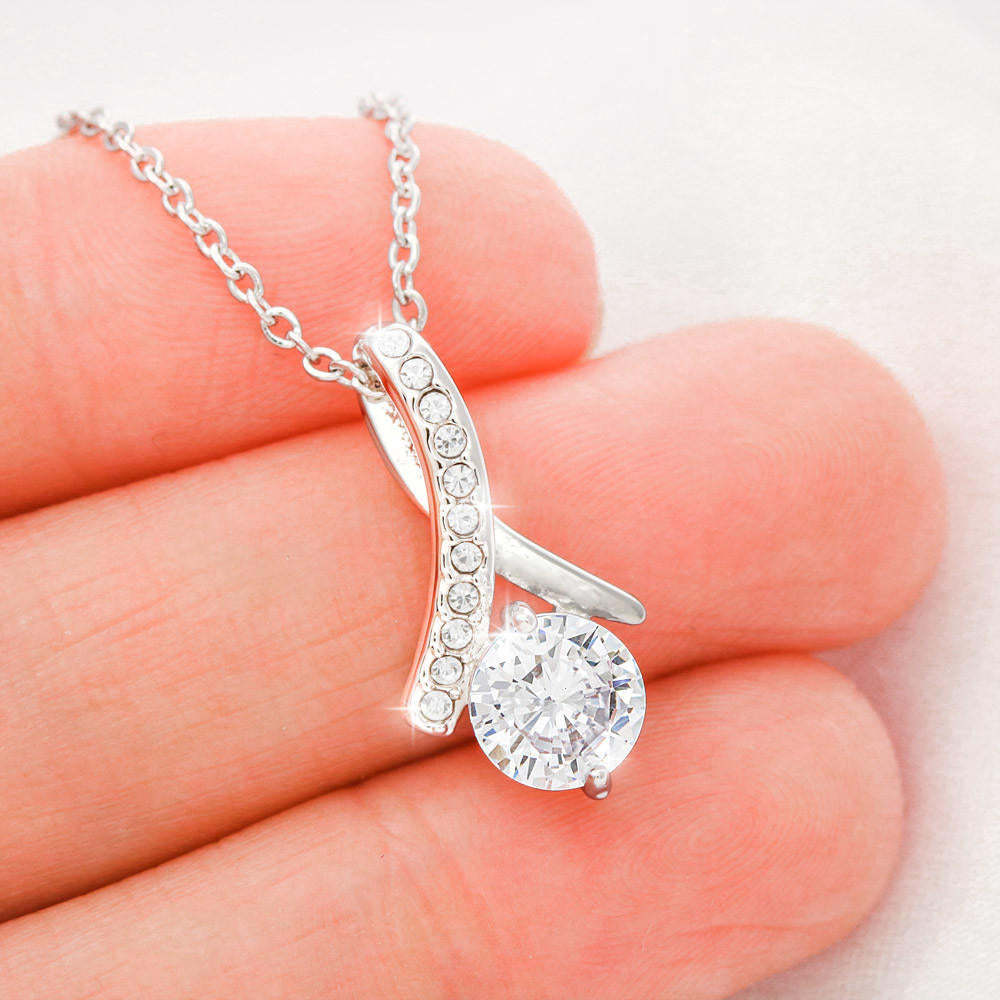 Silver necklace with a pendant held in a hand against a light background