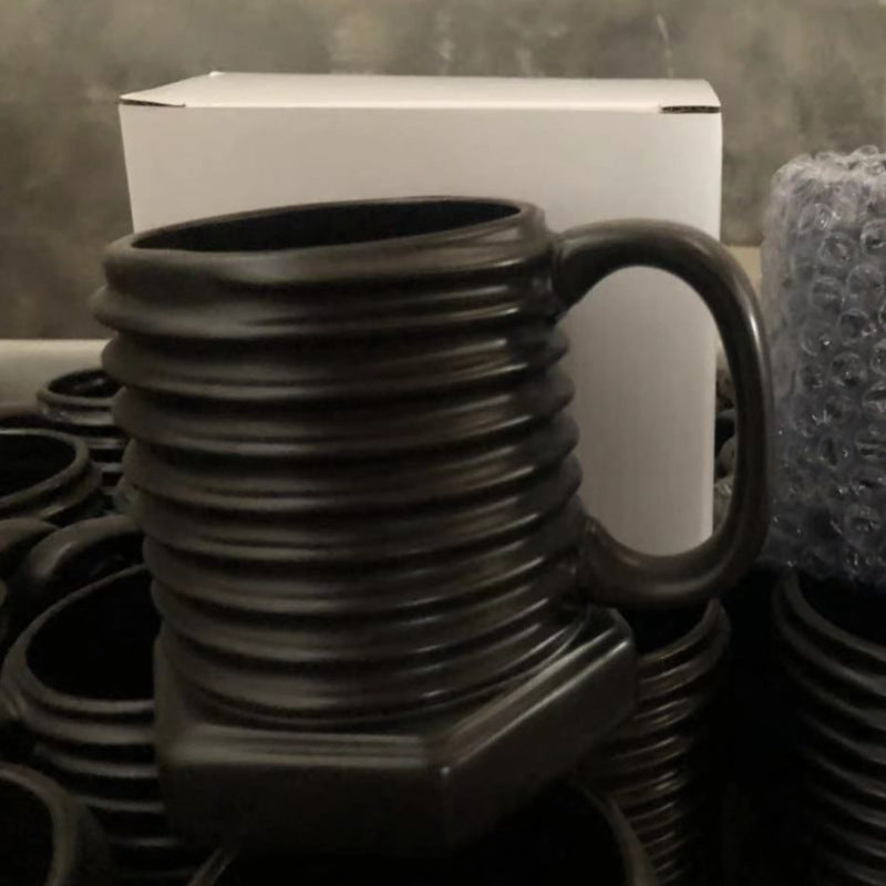 Stack of black ceramic mugs with a white box in the background