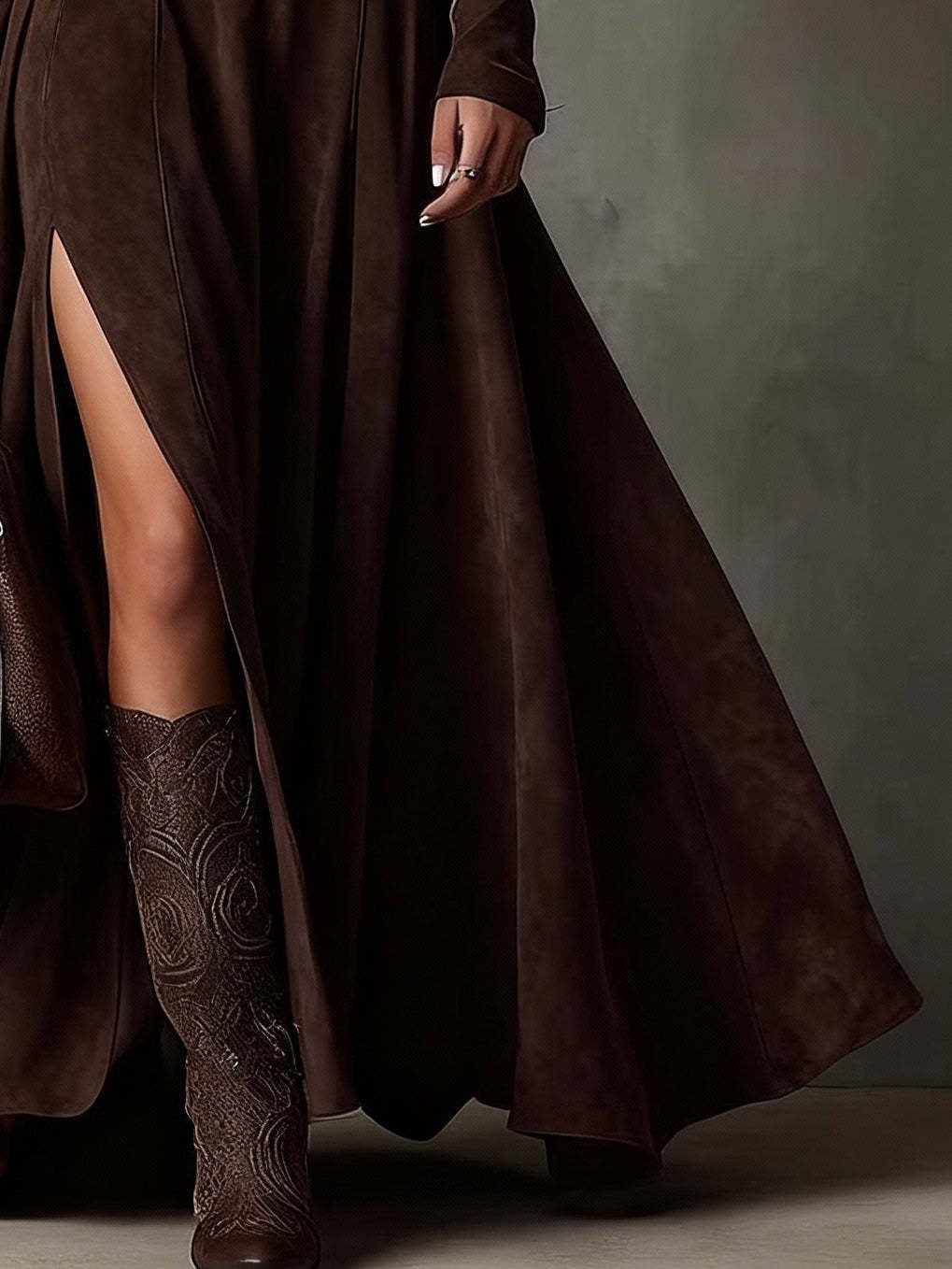 Person wearing a long brown coat and matching knee-high boots against a gray background
