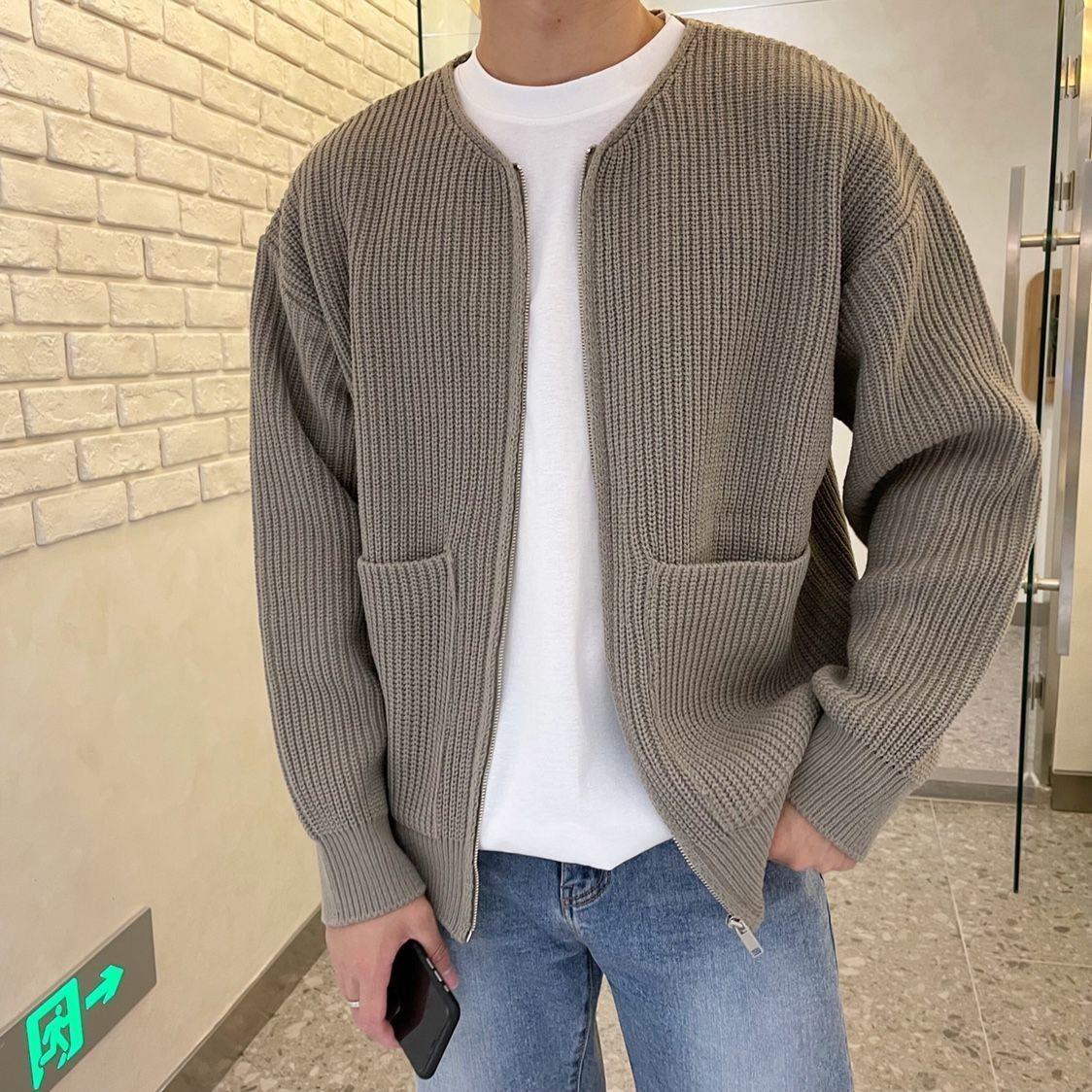 Person wearing a brown knitted cardigan over a white shirt, standing indoors.