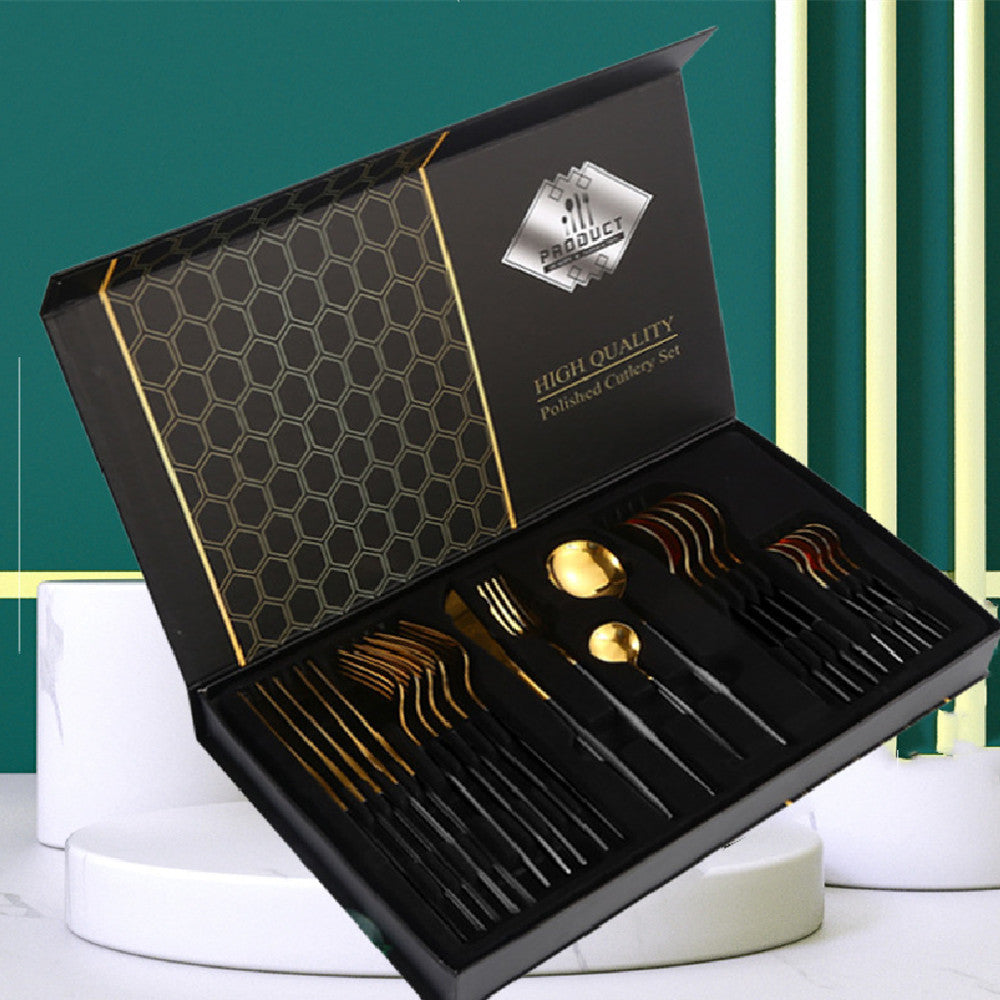 Set of gold and black cutlery in a branded box on a white and green background