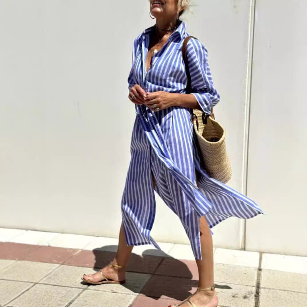 Woman wearing a blue and white striped dress against a white wall.