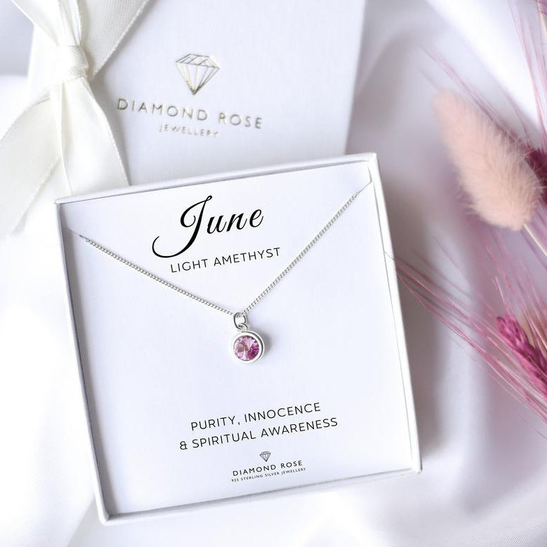 Diamond Rose jewelry box with a necklace featuring an emerald stone on a white background.