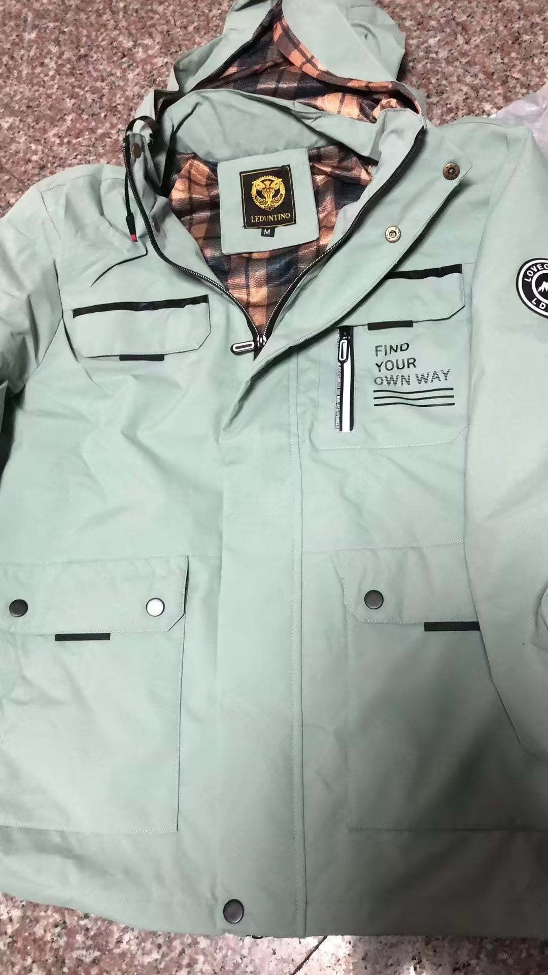 Light green jacket with plaid lining on a textured surface