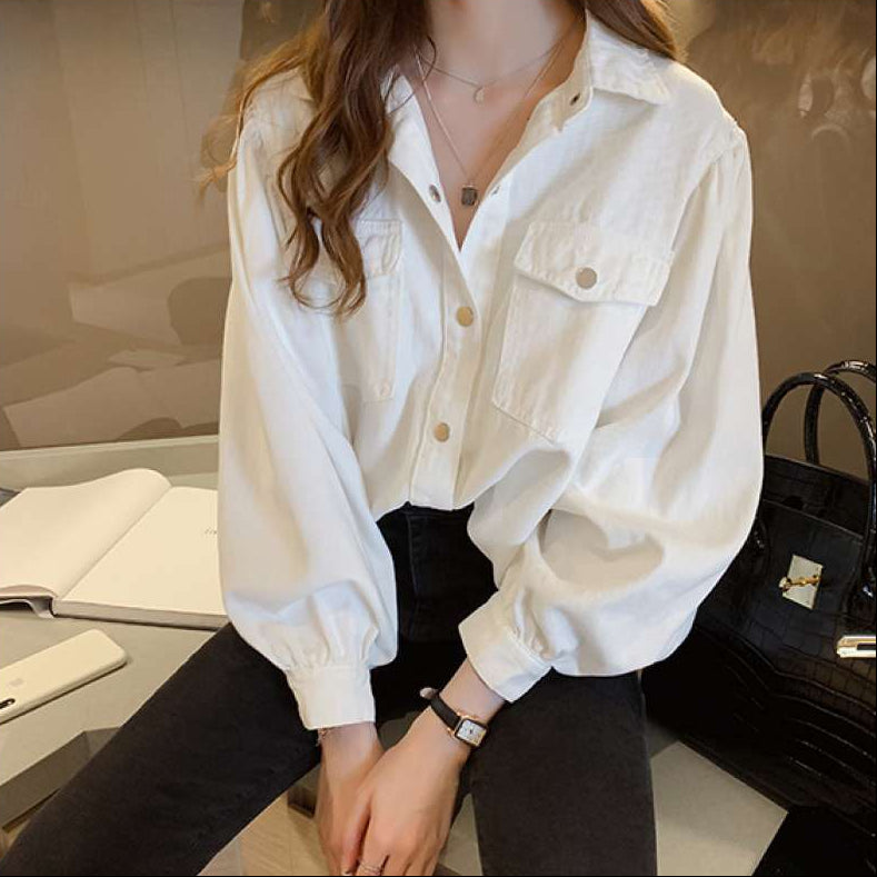 Person wearing a white shirt sitting in an indoor setting with a blurred background