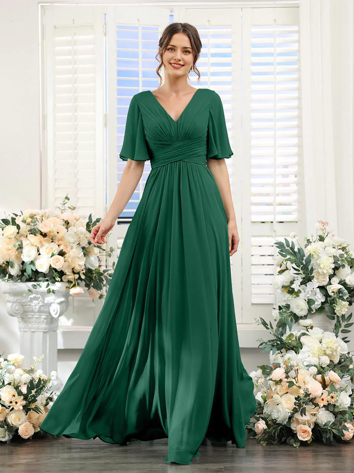Woman wearing a green dress standing in front of floral decorations.